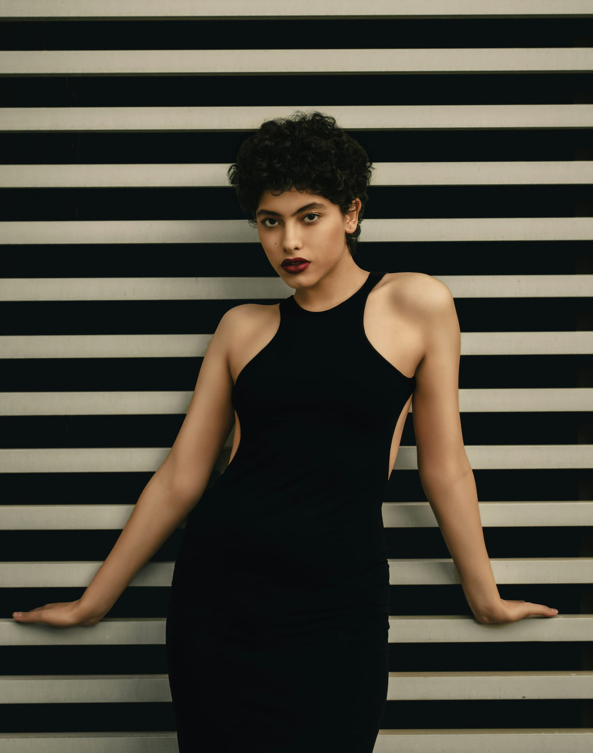 Model wearing black shapewear dress against striped background